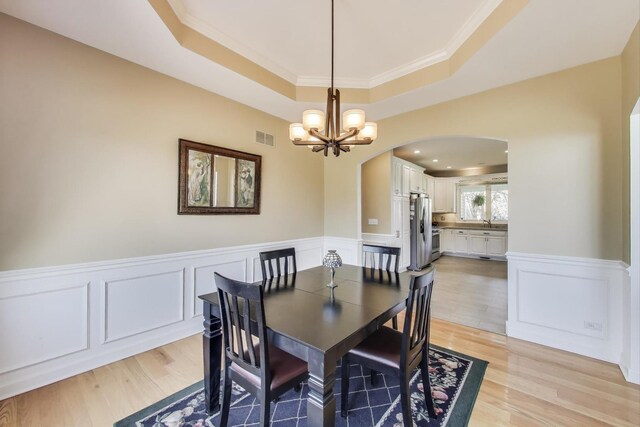2502 S Hidden Trl, Spring Grove, IL 60081 - dining space with visible vents, a chandelier, light wood-style flooring, arched walkways, and a raised ceiling