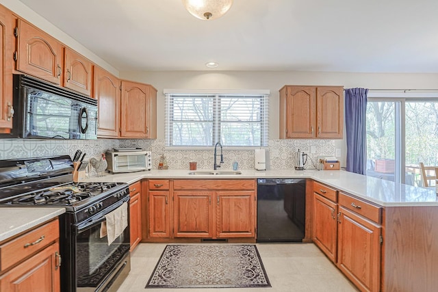 kitchen with a peninsula, a wealth of natural light, a sink, and black appliances