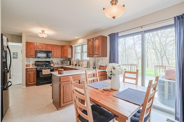kitchen featuring tasteful backsplash, a sink, light countertops, a toaster, and black appliances