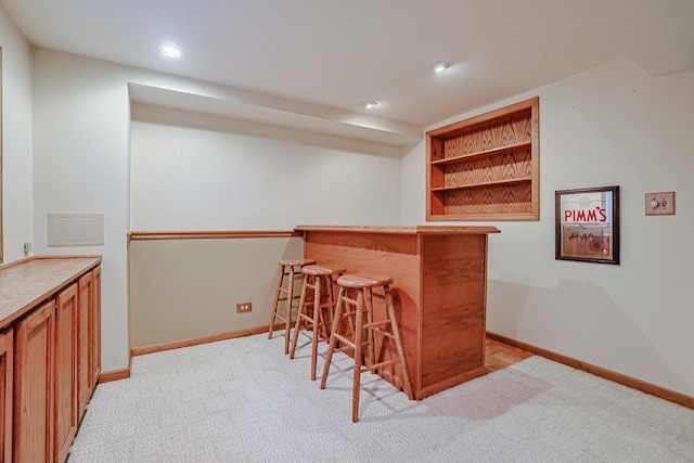 bar featuring recessed lighting, baseboards, light colored carpet, and a bar