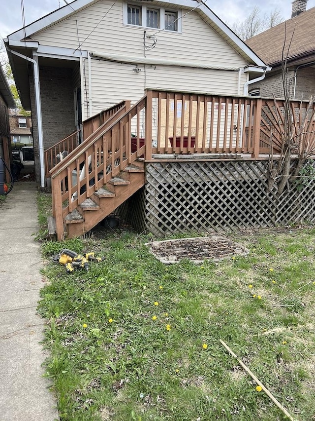 rear view of house with a lawn, stairs, and a wooden deck