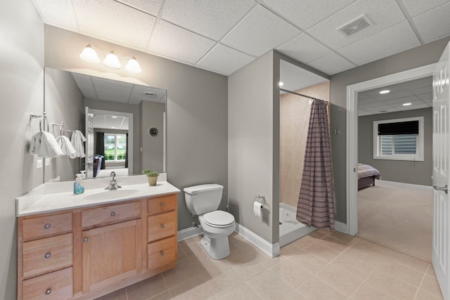 bathroom with a shower stall, a drop ceiling, toilet, vanity, and tile patterned flooring
