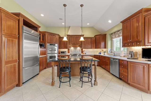 kitchen with appliances with stainless steel finishes, backsplash, a breakfast bar area, a kitchen island, and vaulted ceiling