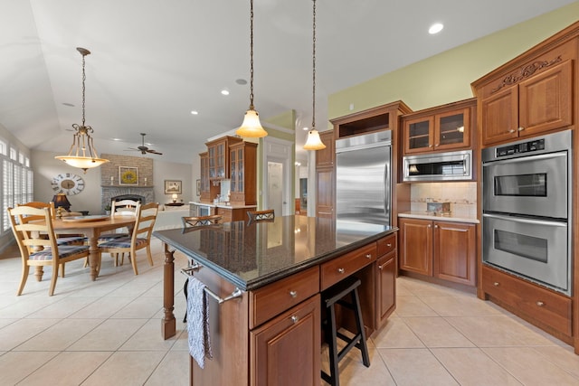 kitchen featuring built in appliances, light tile patterned floors, ceiling fan, a breakfast bar, and tasteful backsplash