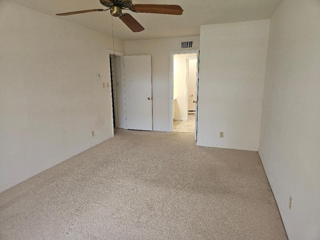carpeted spare room with ceiling fan, visible vents, and baseboards