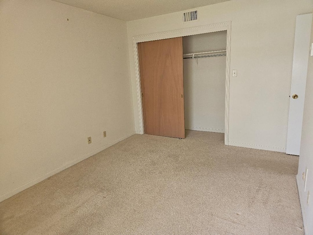 unfurnished bedroom featuring baseboards, visible vents, a closet, and carpet