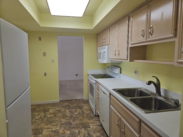 kitchen featuring white appliances, light countertops, a sink, baseboards, and a tray ceiling