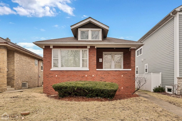 bungalow-style home featuring fence and brick siding
