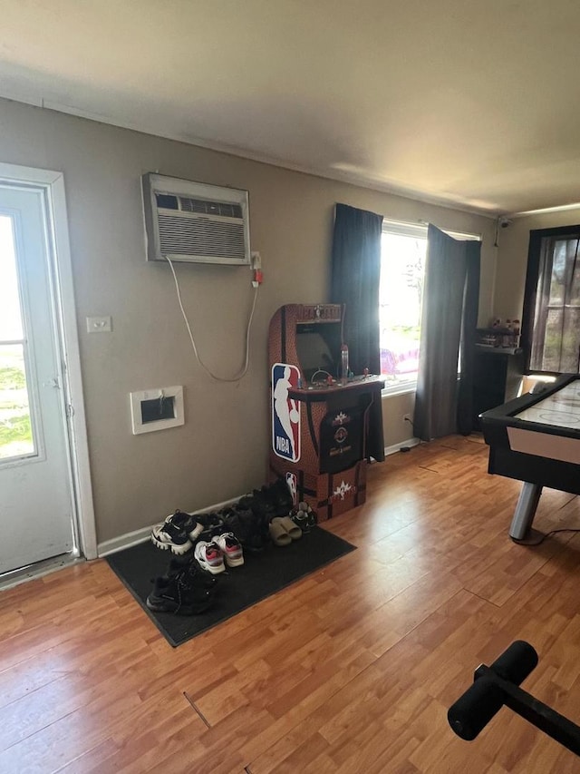 recreation room with a wall unit AC and wood finished floors
