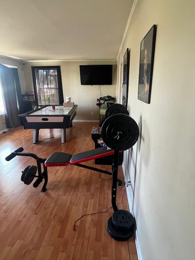 workout room featuring wood finished floors, baseboards, and ornamental molding