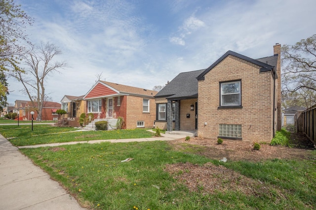view of front of house featuring a chimney, brick siding, and a front lawn