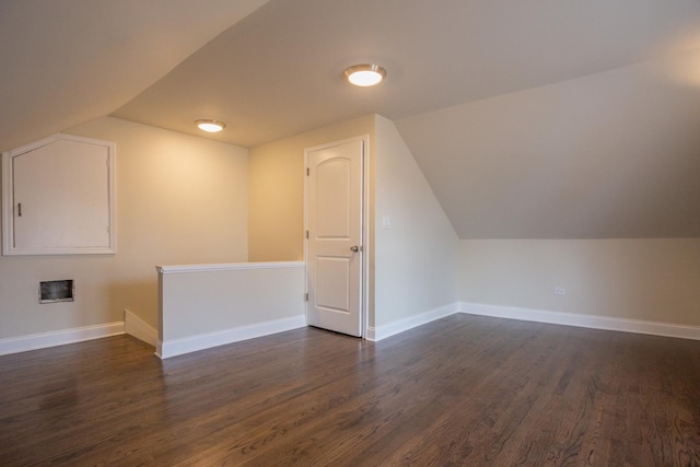 additional living space with dark wood finished floors, baseboards, and vaulted ceiling