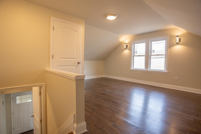 bonus room with dark wood-style flooring, lofted ceiling, and baseboards