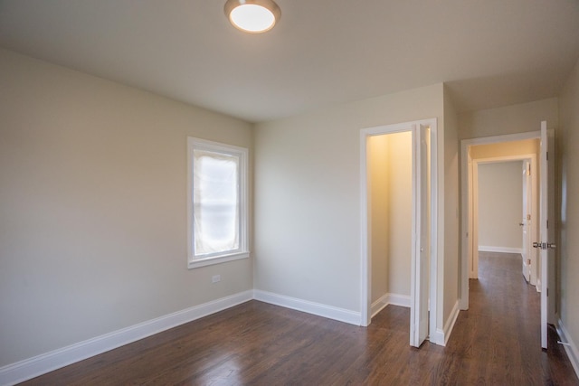 unfurnished bedroom with dark wood-style flooring and baseboards