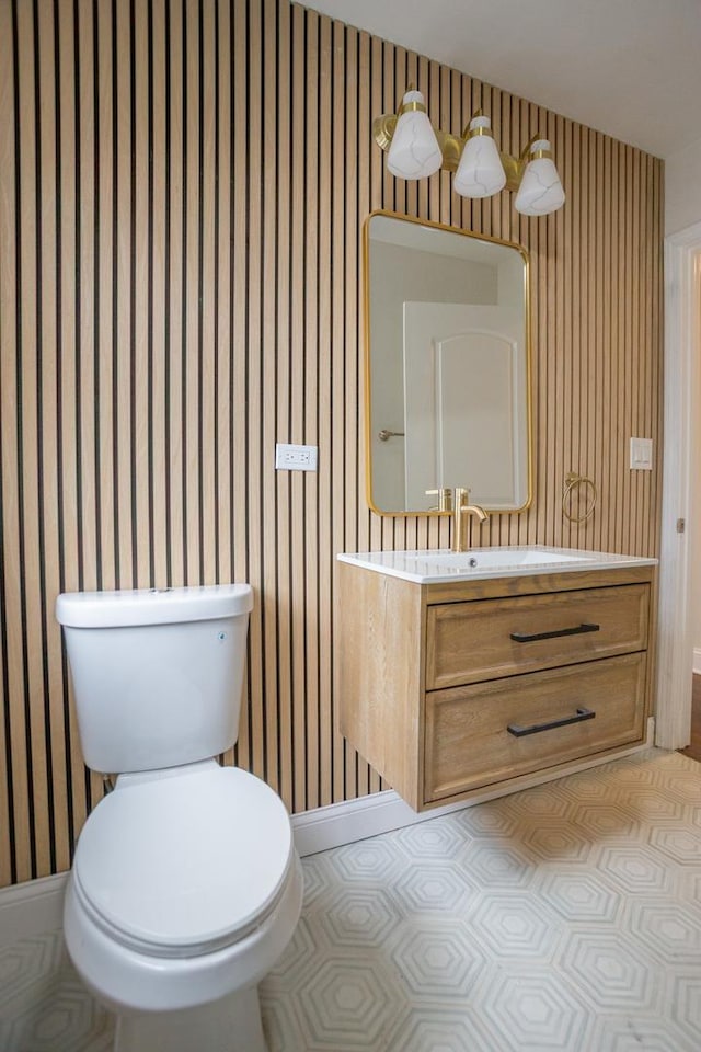 bathroom featuring vanity, toilet, wallpapered walls, and baseboards
