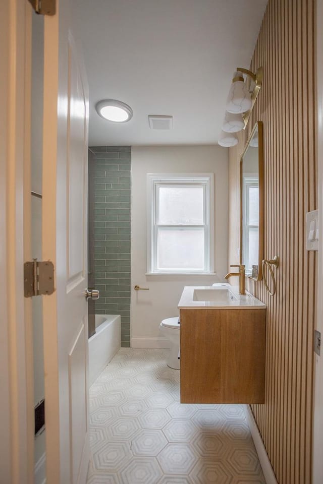 bathroom with vanity, shower / bath combination, toilet, visible vents, and baseboards