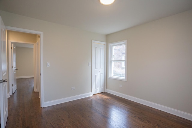 unfurnished bedroom with a closet, baseboards, and dark wood finished floors
