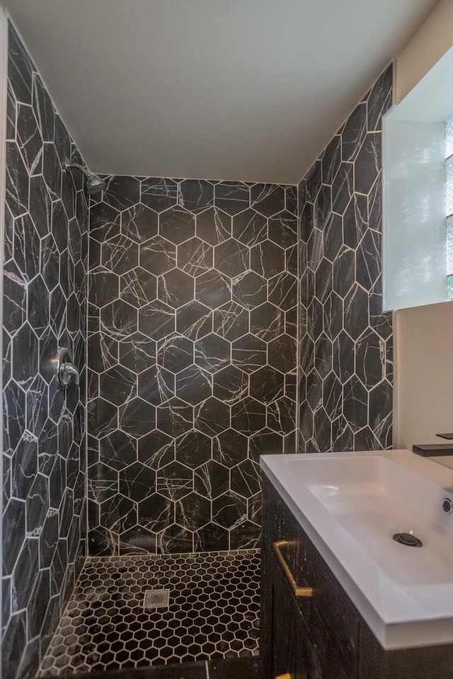 bathroom with tile walls, tiled shower, and vanity