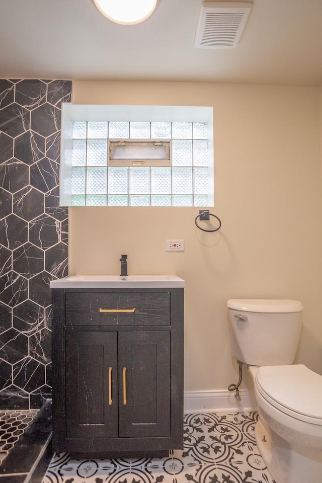 bathroom with baseboards, visible vents, a wealth of natural light, and toilet