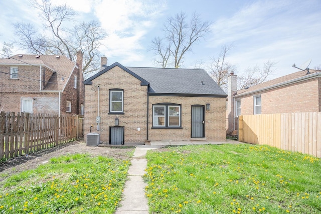 back of house featuring a chimney, brick siding, a fenced backyard, and a yard
