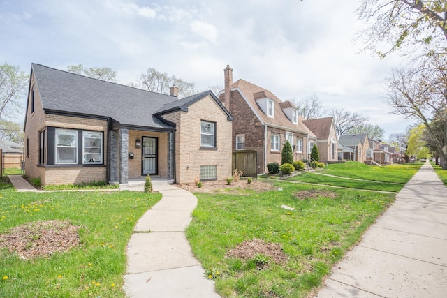 view of front of house with brick siding, roof with shingles, a front lawn, and a residential view