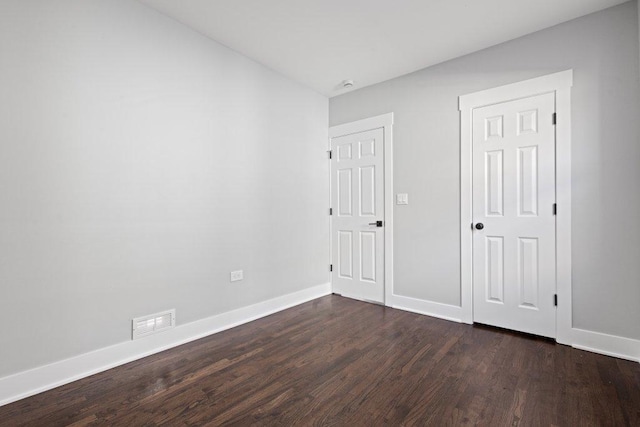 unfurnished bedroom featuring dark wood-type flooring, visible vents, and baseboards