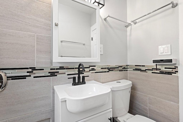half bathroom with toilet, tile walls, and vanity