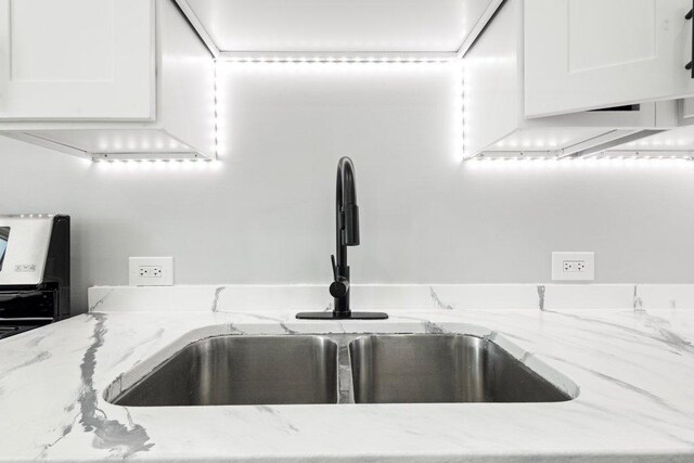 details with white cabinets, light stone countertops, and a sink