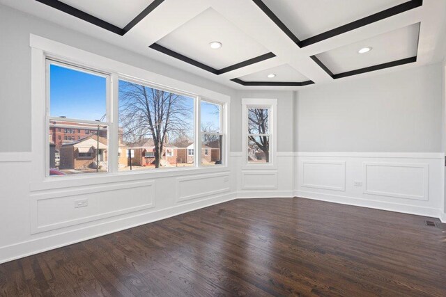 unfurnished room with dark wood finished floors, coffered ceiling, a decorative wall, wainscoting, and beamed ceiling