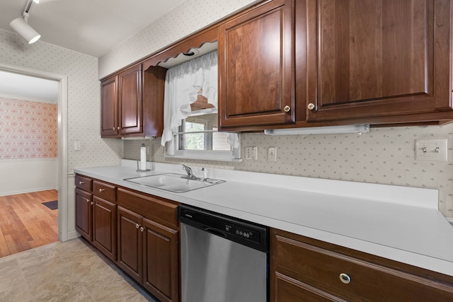 kitchen with stainless steel dishwasher, wallpapered walls, light wood-style floors, light countertops, and a sink