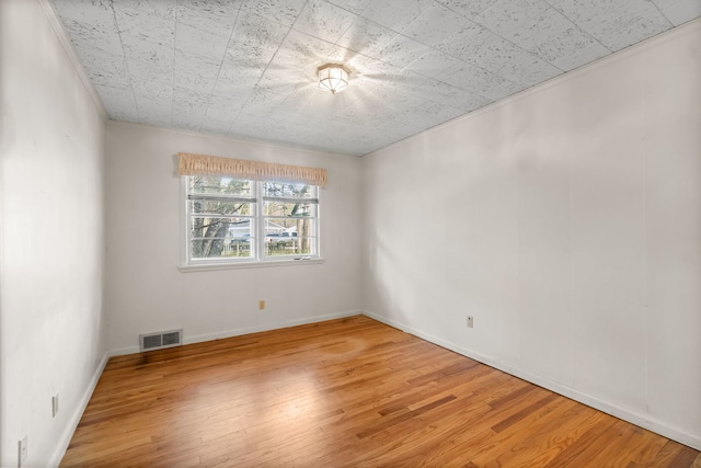 empty room with visible vents, baseboards, and light wood-style floors