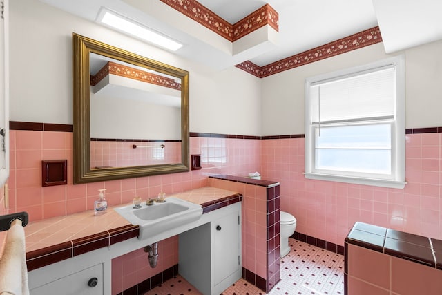 bathroom featuring toilet, tile walls, and wainscoting