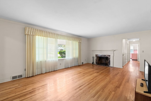 unfurnished living room featuring visible vents, light wood-type flooring, crown molding, and a high end fireplace