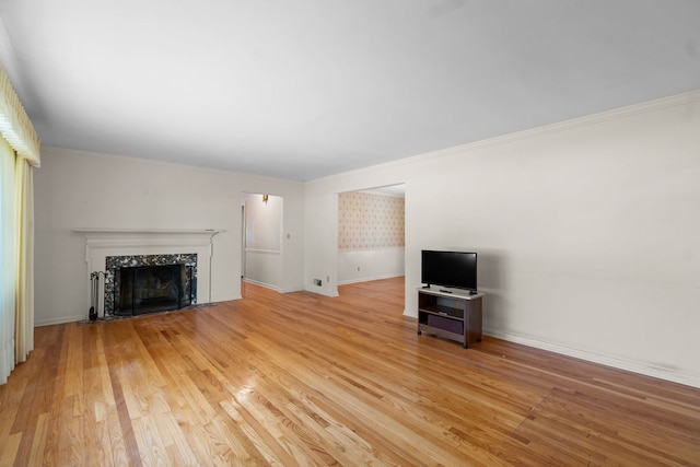 unfurnished living room featuring ornamental molding, a high end fireplace, and light wood-style flooring