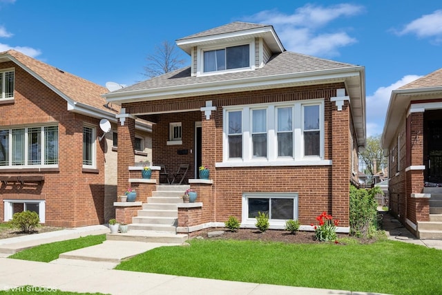 bungalow-style house featuring roof with shingles, a front yard, a porch, and brick siding