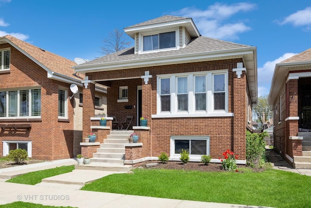 bungalow-style house with covered porch, brick siding, a front yard, and roof with shingles