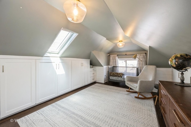 interior space featuring a wainscoted wall, vaulted ceiling with skylight, and dark wood-style floors
