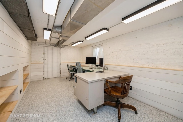 office space with wooden walls and light speckled floor
