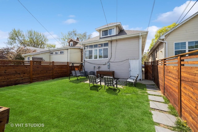 back of house featuring a fenced backyard, a yard, and roof with shingles