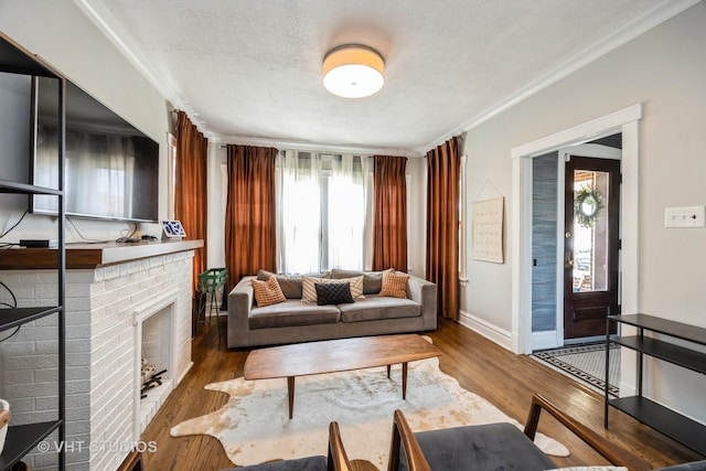 living area with crown molding, wood finished floors, a fireplace, baseboards, and a textured ceiling
