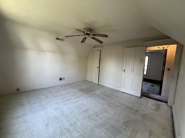additional living space featuring visible vents, a ceiling fan, vaulted ceiling, and light carpet