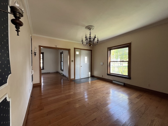unfurnished dining area featuring hardwood / wood-style flooring, crown molding, visible vents, baseboards, and a notable chandelier