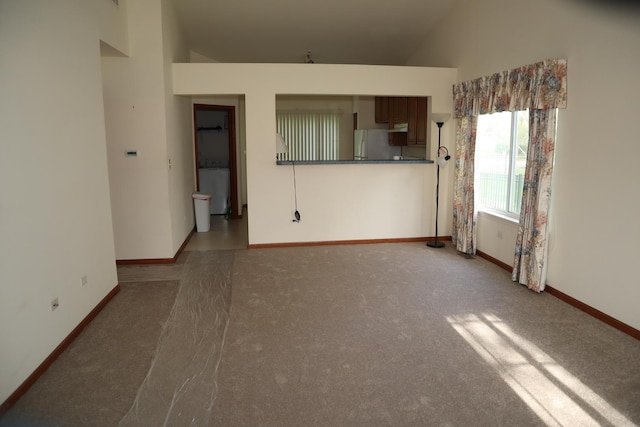 unfurnished living room featuring baseboards, high vaulted ceiling, and carpet floors
