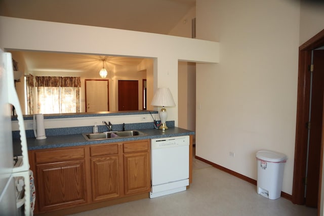 kitchen featuring a sink, brown cabinetry, baseboards, dark countertops, and dishwasher