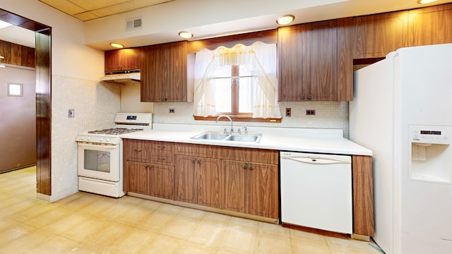kitchen featuring white appliances, a sink, under cabinet range hood, light countertops, and light flooring