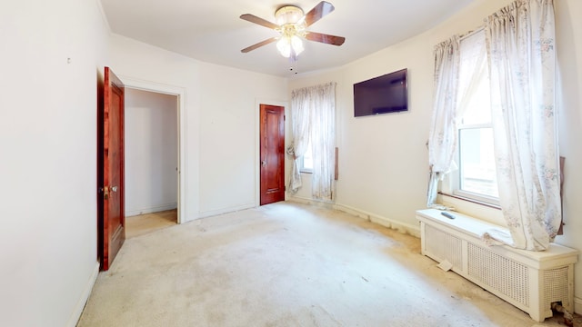 unfurnished bedroom featuring radiator, baseboards, carpet, and a ceiling fan