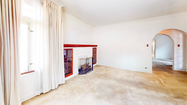 unfurnished living room with ornamental molding, arched walkways, baseboards, a fireplace, and light carpet