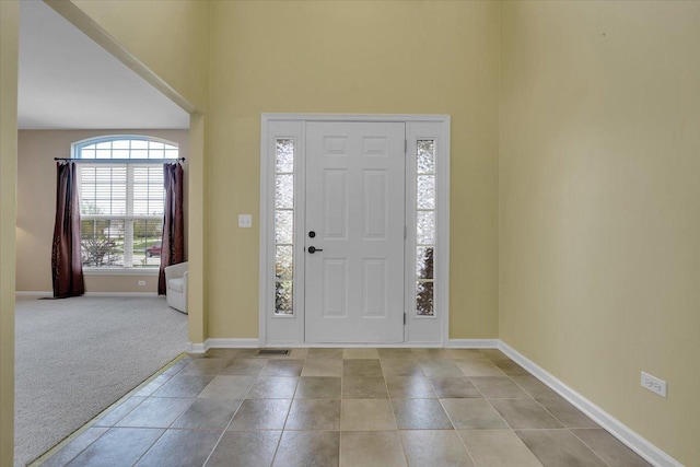 entryway featuring baseboards, a high ceiling, carpet, and visible vents