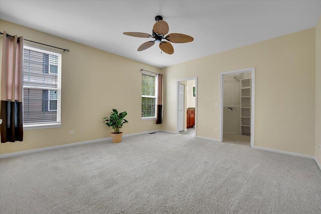 unfurnished bedroom featuring carpet flooring, baseboards, a spacious closet, and ensuite bath