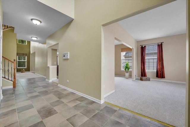 hall featuring baseboards, tile patterned floors, and stairs
